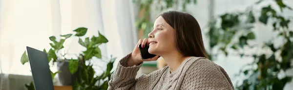A young woman in a wheelchair sits at home, smiling as she talks on her cell phone. — Stock Photo