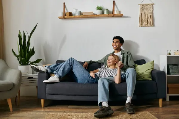 A young multicultural couple relaxes and enjoys each others company on a comfortable sofa in their modern apartment. — Stock Photo