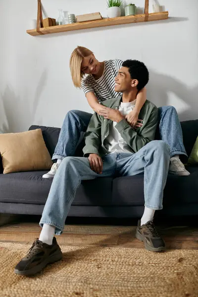 A young couple, a man and a woman, cuddle on a sofa in a modern apartment. — Stock Photo