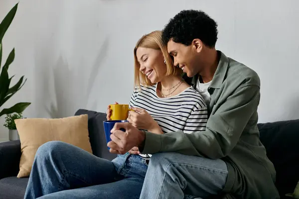A young interracial couple enjoys coffee and each others company in their modern apartment. — Stock Photo