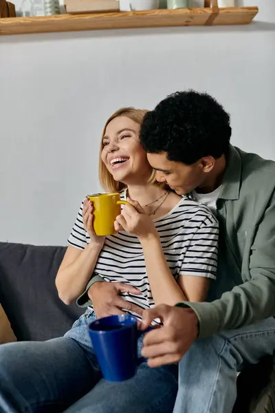 Una joven pareja multicultural se ríe y disfruta de su buen día en un apartamento moderno. - foto de stock