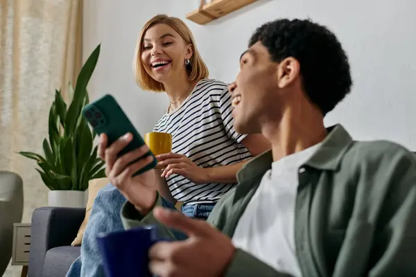 A young interracial couple enjoys a moment of laughter and connection while relaxing in their modern apartment. — Stock Photo
