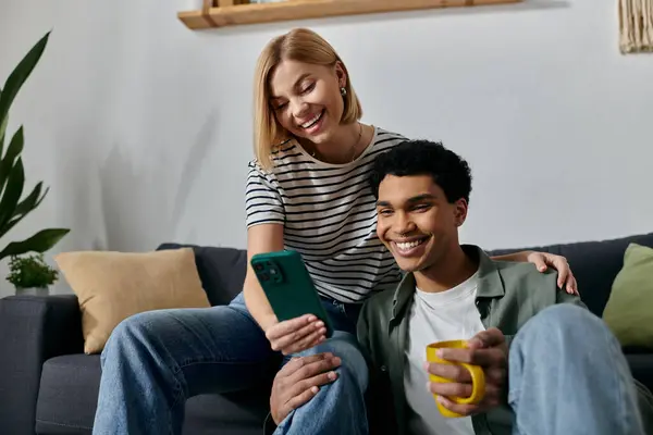 A young multicultural couple relaxes on a couch in a modern apartment, enjoying a cozy evening together. — Stock Photo