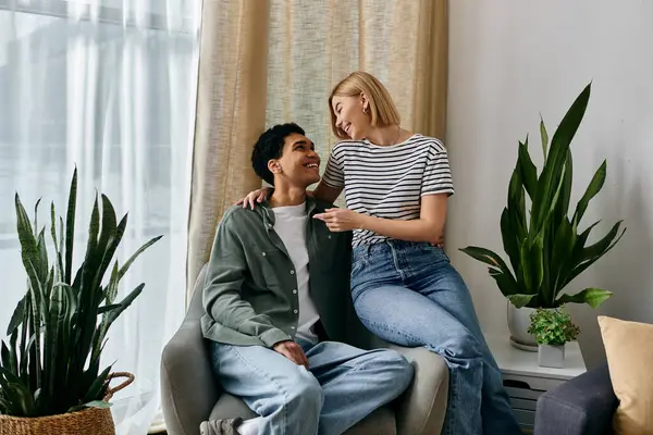 A young interracial couple enjoys a moment of intimacy and laughter in their modern apartment, bathed in natural light. — Stock Photo