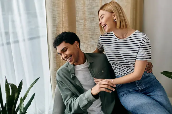 A young multicultural couple shares a moment of laughter together in their modern apartment. — Stock Photo