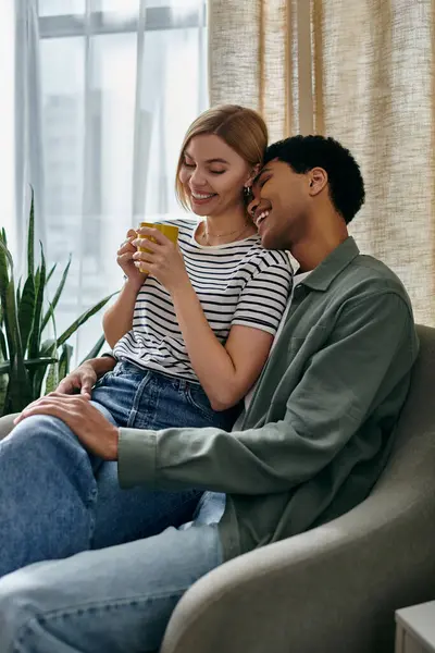 A young, multicultural couple shares a cup of coffee and a loving moment in their modern apartment. — Stock Photo