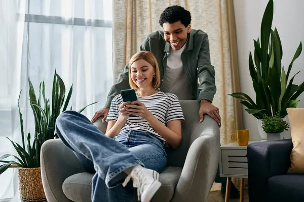 A young couple, relaxes in a modern apartment, the woman scrolling on her phone while her man looks on. — Stock Photo