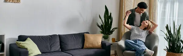 A young multicultural couple enjoys a lighthearted moment in their modern apartment, filled with natural light and greenery. — Stock Photo