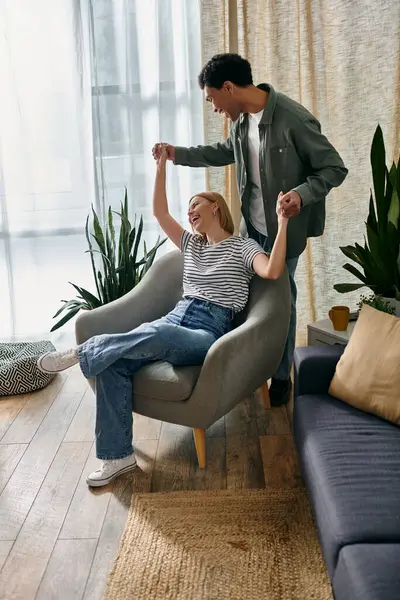 A young multicultural couple playfully interacts in their modern apartment, showcasing a lighthearted and intimate moment. — Stock Photo