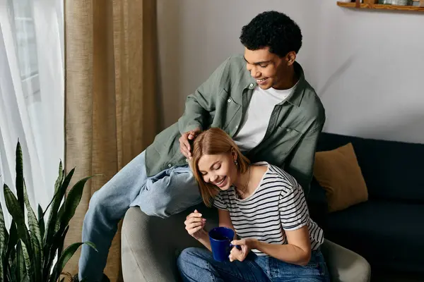 A young couple enjoys a cozy moment in their modern apartment, laughing and sharing a cup of coffee. — Stock Photo