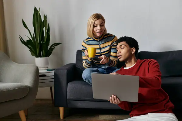 A happy multicultural couple enjoys a relaxing afternoon in their modern apartment, browsing the internet on a laptop. — Stock Photo