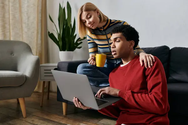 A happy multicultural couple spends quality time together in a modern apartment, looking at a laptop and enjoying each others company. — Stock Photo