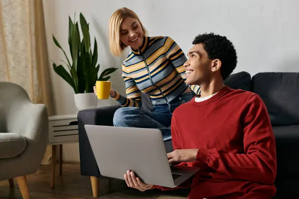 A happy, multicultural couple enjoys quality time together in a modern apartment, using a laptop. — Stock Photo