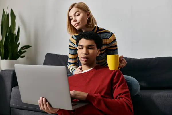 A multicultural couple relaxes in their modern apartment, enjoying a moment of shared connection while using a laptop. — Stock Photo