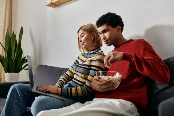 Una pareja feliz y multicultural disfruta de una noche de cine en su acogedor y moderno apartamento. - foto de stock