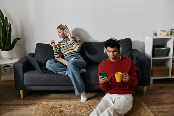 A multicultural couple relaxes in their modern apartment, enjoying headphones, coffee, and their own company. — Stock Photo