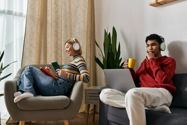 A multicultural couple enjoys a quiet afternoon in their modern apartment, each engaged in their own activity. — Stock Photo