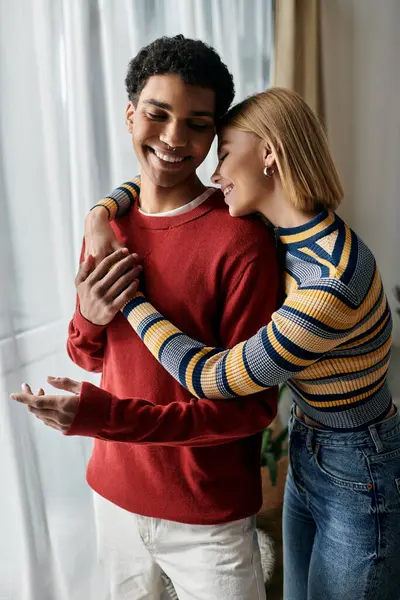 A happy multicultural couple embraces in their modern apartment, enjoying a moment of intimacy and love. — Stock Photo