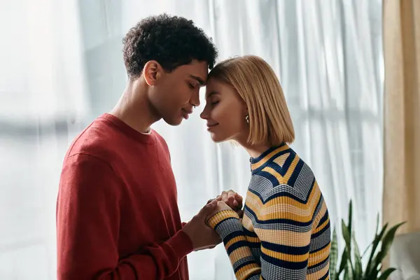 A happy multicultural couple stands in their apartment, their foreheads touching as they share a tender moment. — Stock Photo