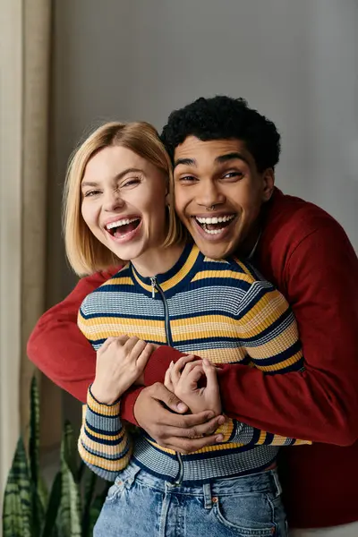 A happy multicultural couple laughs together in a modern apartment. — Stock Photo