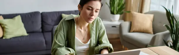 A woman sits at a desk in her living room, working on a laptop. — Stock Photo