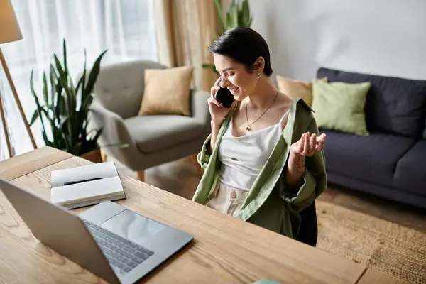 A woman smiles as she talks on the phone while working at her home office. — Stock Photo