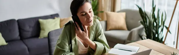 A woman works from home, taking a call while sitting at a desk. — Stock Photo