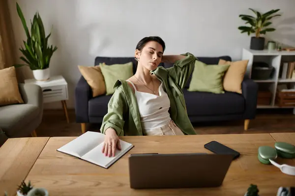 A young woman takes a break from her work at home, leaning back in her chair and stretching. — Stock Photo