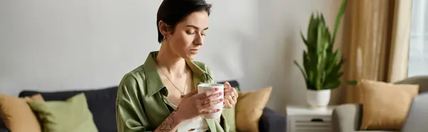A woman sits on a couch, taking a break with a cup of coffee. — Stock Photo