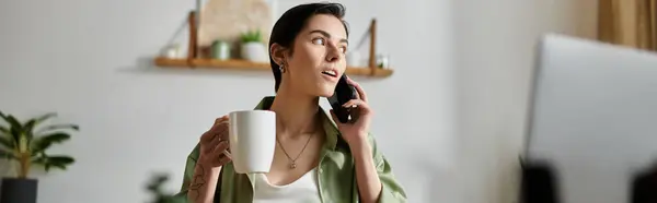 A woman sits at home, holding a mug and talking on her phone. — Stock Photo