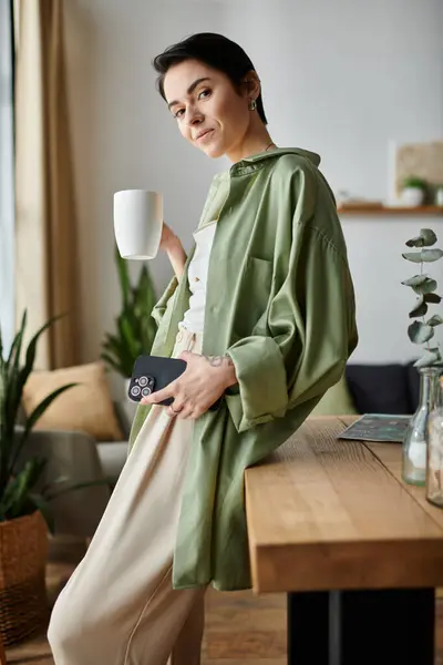 Une femme profite d'une tasse de café tout en travaillant à la maison. — Photo de stock
