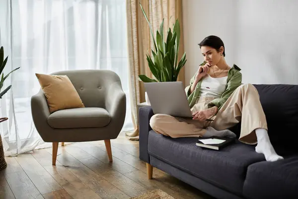 A woman works remotely from home, thoughtfully looking at her laptop. — Stock Photo