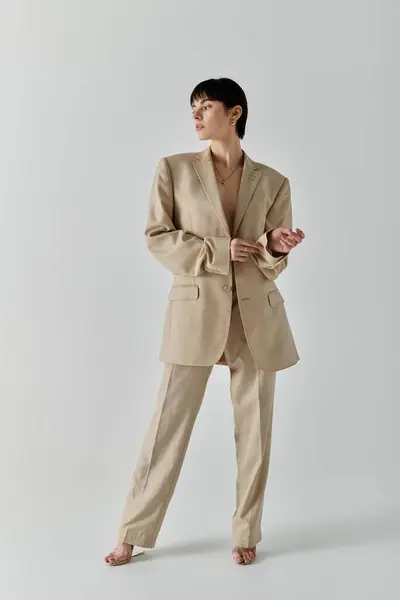 Stylish woman in beige suit poses confidently against white backdrop. — Stock Photo