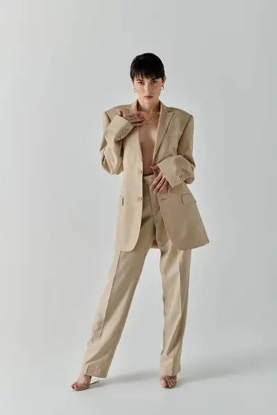 Une femme en costume beige pose sur fond blanc. — Photo de stock