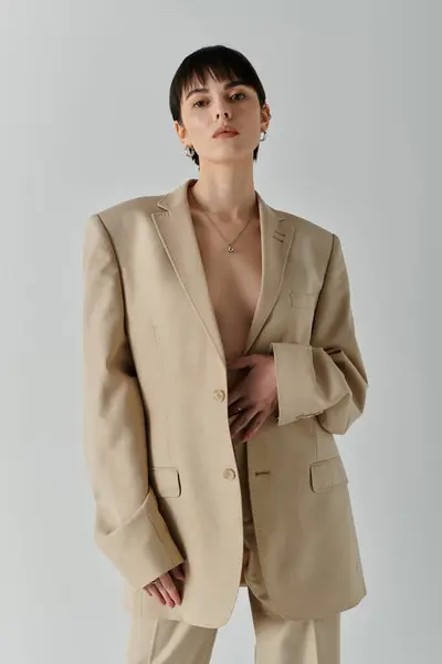 A woman poses confidently in a beige blazer, showcasing a minimalist style. — Stock Photo