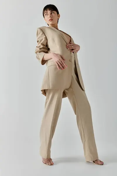 A woman in a tan suit poses confidently in a studio setting. — Stock Photo