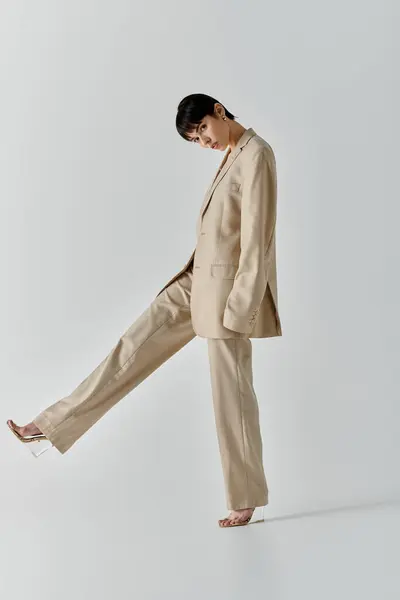A woman in a beige suit poses against a white backdrop. — Stock Photo