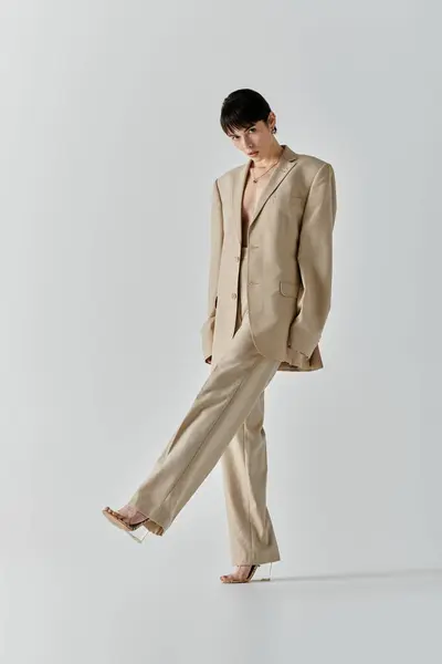 A woman in a beige suit walks forward, her leg extended in a confident pose. — Stock Photo