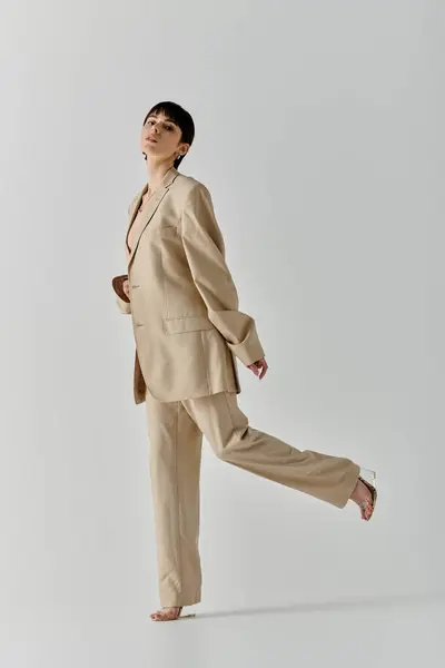A woman in a tan suit poses with a confident and stylish expression. — Stock Photo