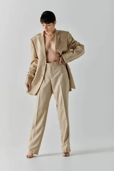 A woman in a tan suit stands confidently in front of a white backdrop. — Stock Photo