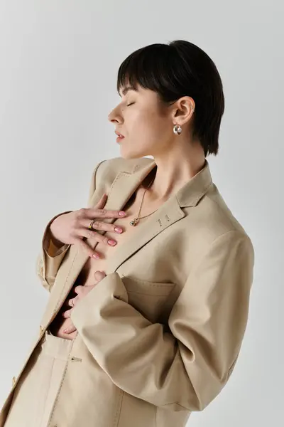 A woman in a tan blazer poses against a white backdrop. — Stock Photo