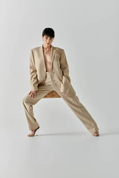 A woman in a beige suit poses confidently against a white backdrop. — Stock Photo