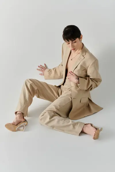 Une femme pose dans un costume beige sur fond blanc. — Photo de stock