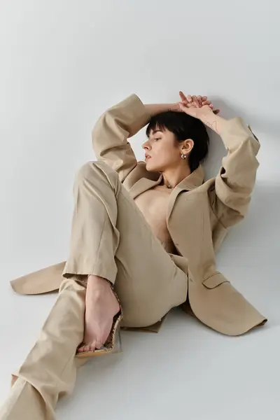 Une jolie femme portant un costume bronzé s'assoit sur un fond blanc. — Photo de stock