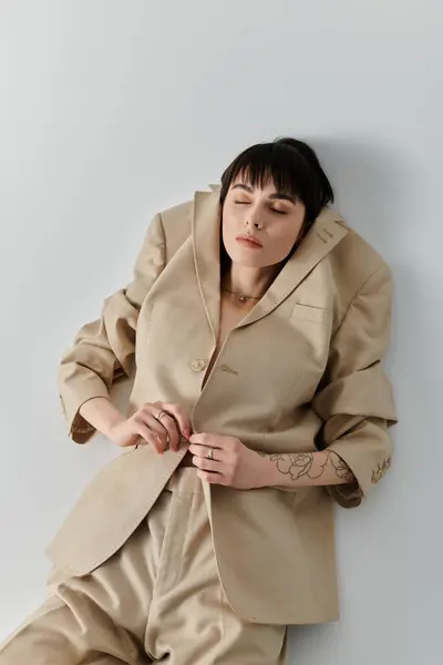 A woman in a beige suit poses against a white wall. — Stock Photo