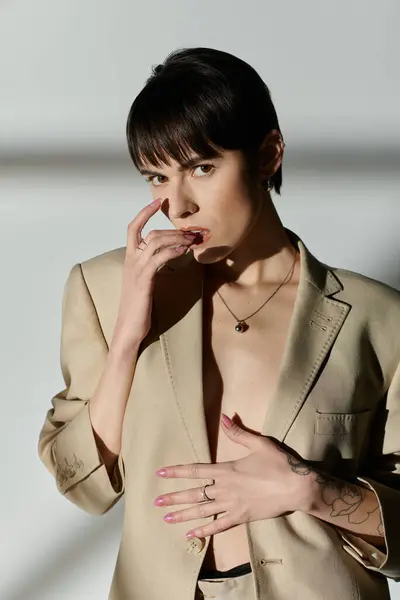 Mujer con el pelo negro corto, chaqueta bronceada, mirando a la cámara. - foto de stock