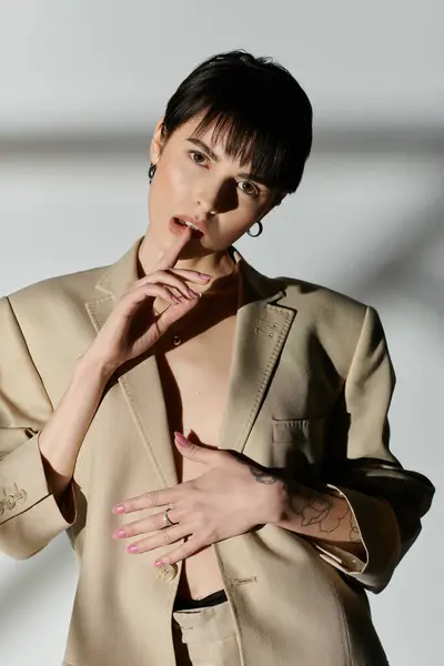 Una mujer con una chaqueta bronceada posa con confianza sobre un fondo blanco. - foto de stock