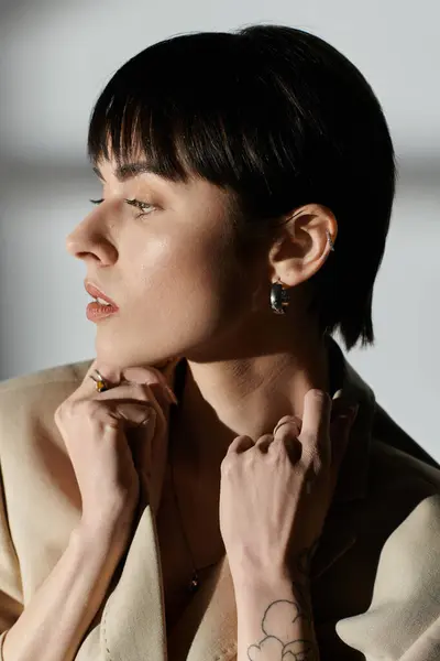 Mujer con el pelo negro en chaqueta beige, mirando pensativamente lejos de la cámara. - foto de stock