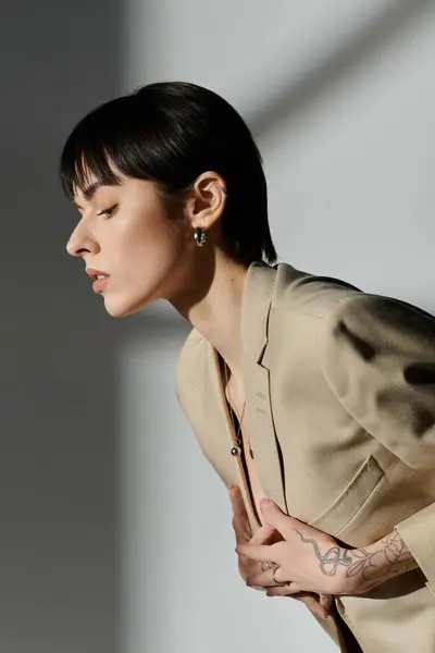 Une femme aux cheveux noirs courts porte un blazer bronzé et pose en studio. — Photo de stock