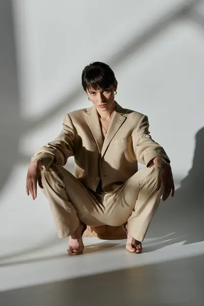 A woman in a beige suit sits on a low platform, her bare feet resting on the ground. — Stock Photo
